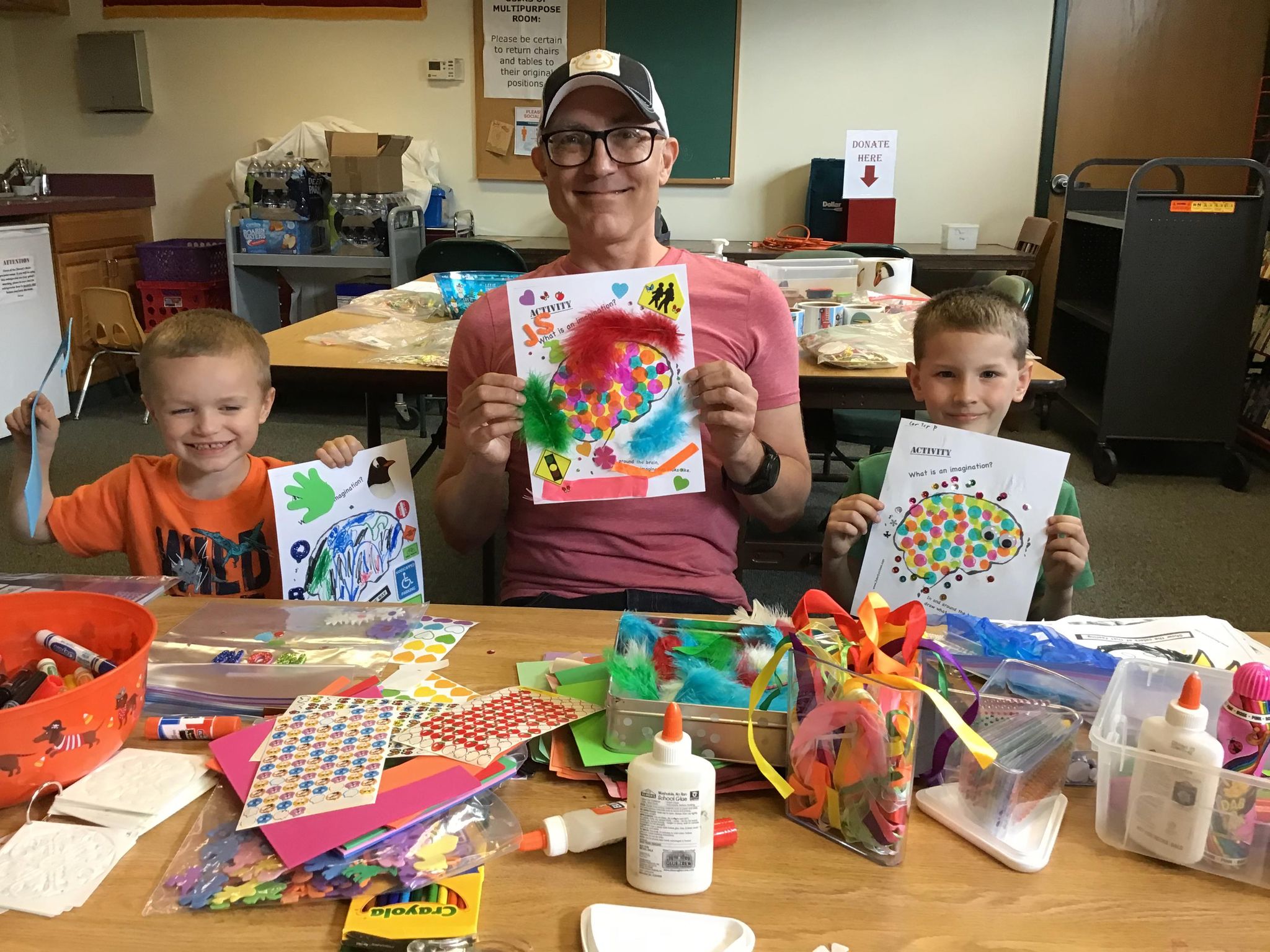 Pictured are John Schlimm with two program attendees showing off their imagination crafts.